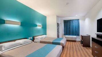 A hotel room with two beds, a TV, and a window with curtains.
