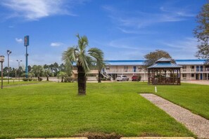 Ein Hotel mit blauem Dach, einer überdachten Außenbereich-Sitzgelegenheit und einem gepflegten Rasen.