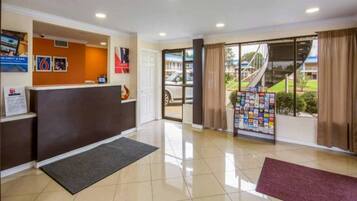 A reception area with a counter, a bulletin board, and a view of the outside through a glass door.