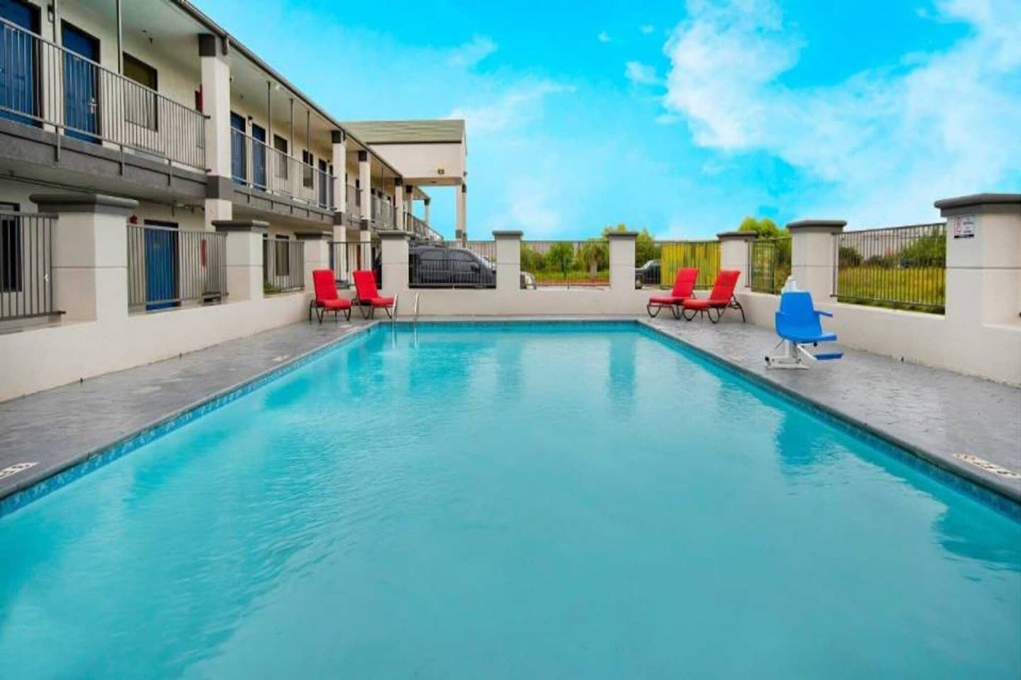 A swimming pool with red lounge chairs and a clear blue sky.