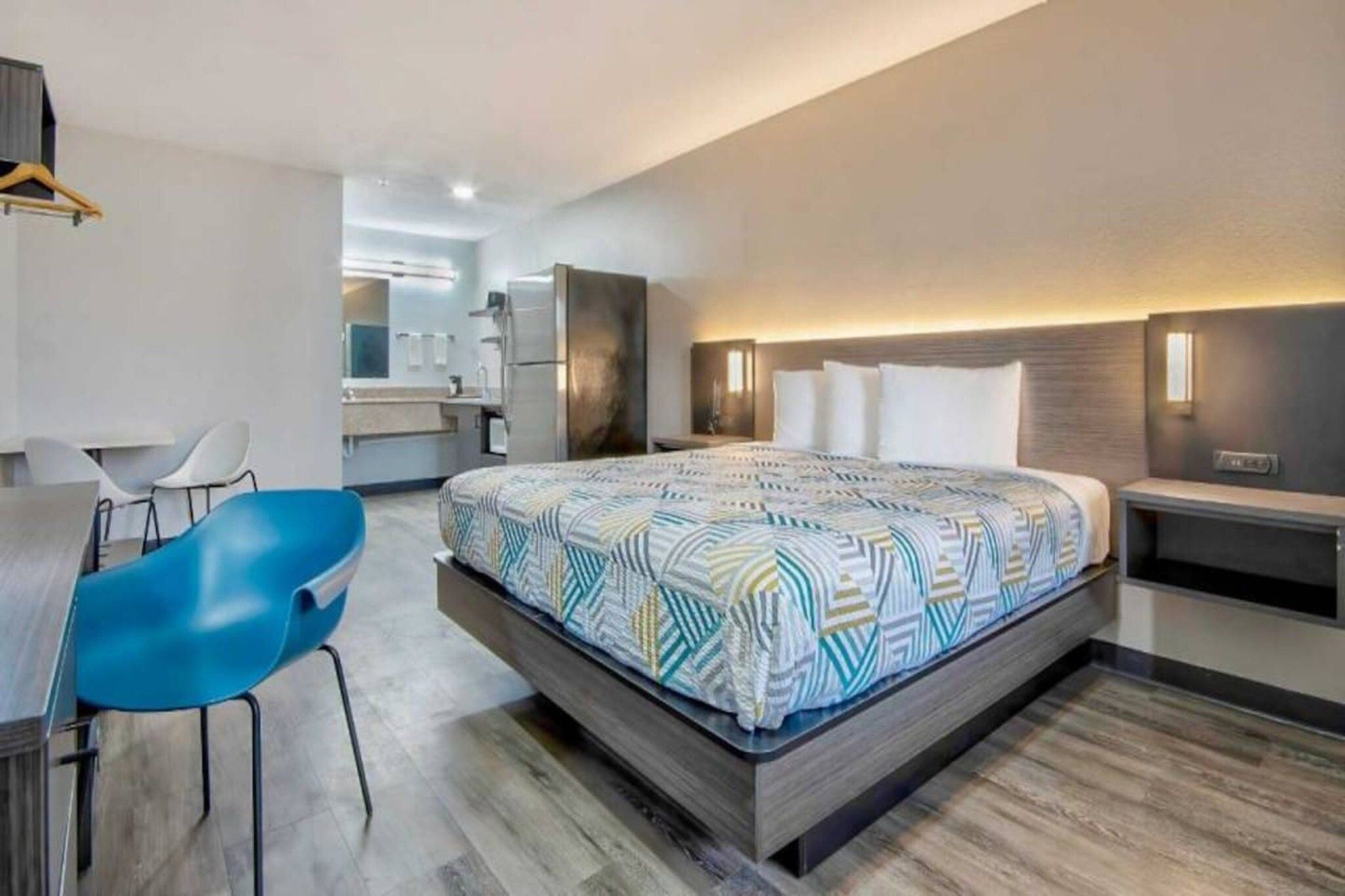 A modern hotel room with a large bed, a desk, and a chair.