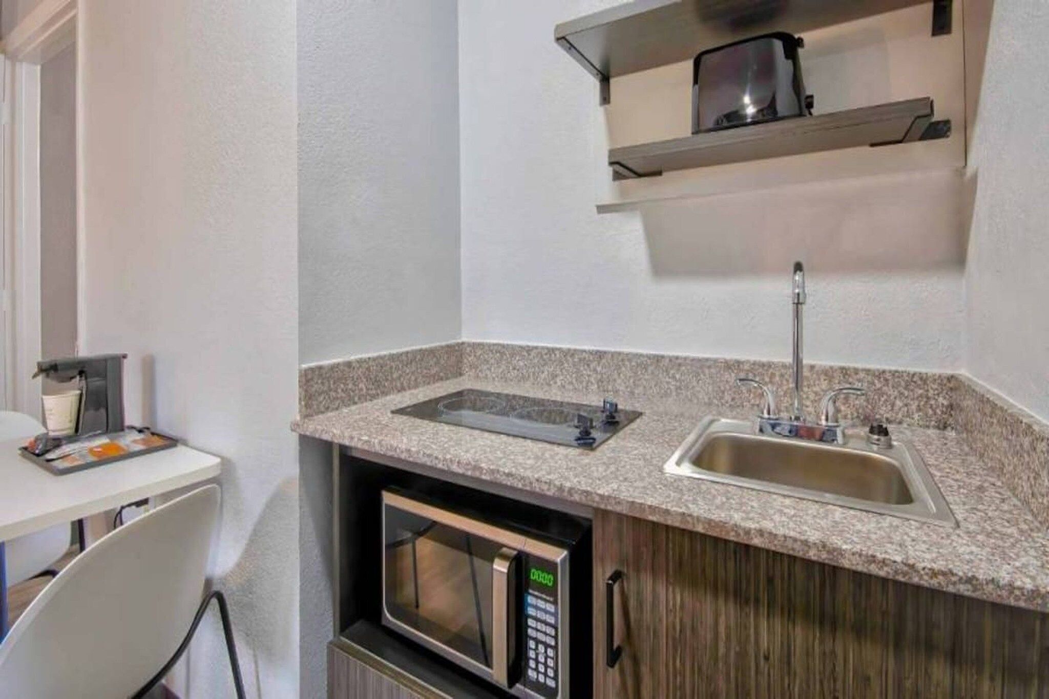 A compact kitchenette with a microwave, a sink, and a stovetop.