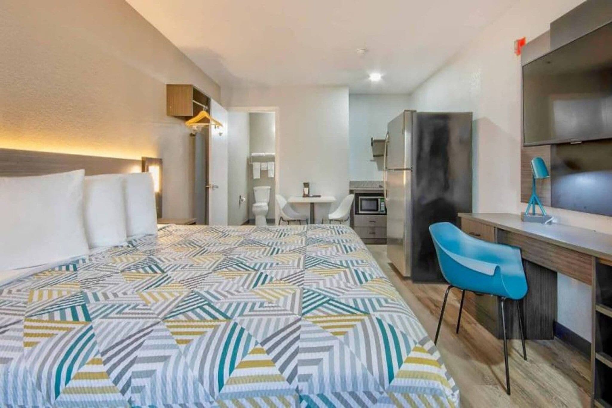 Une chambre d’hôtel comprenant un lit, un bureau, une chaise, une kitchenette et une salle de bain.