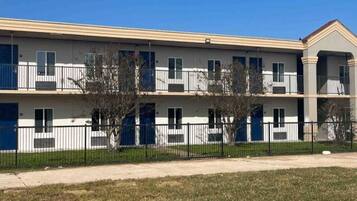 A multi-story building with balconies, a flat roof, and a fenced perimeter.