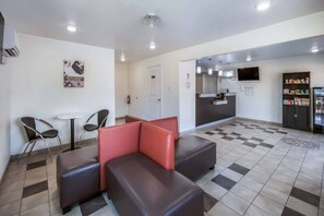 A hotel lobby with a check-in counter, seating area, and a vending machine.