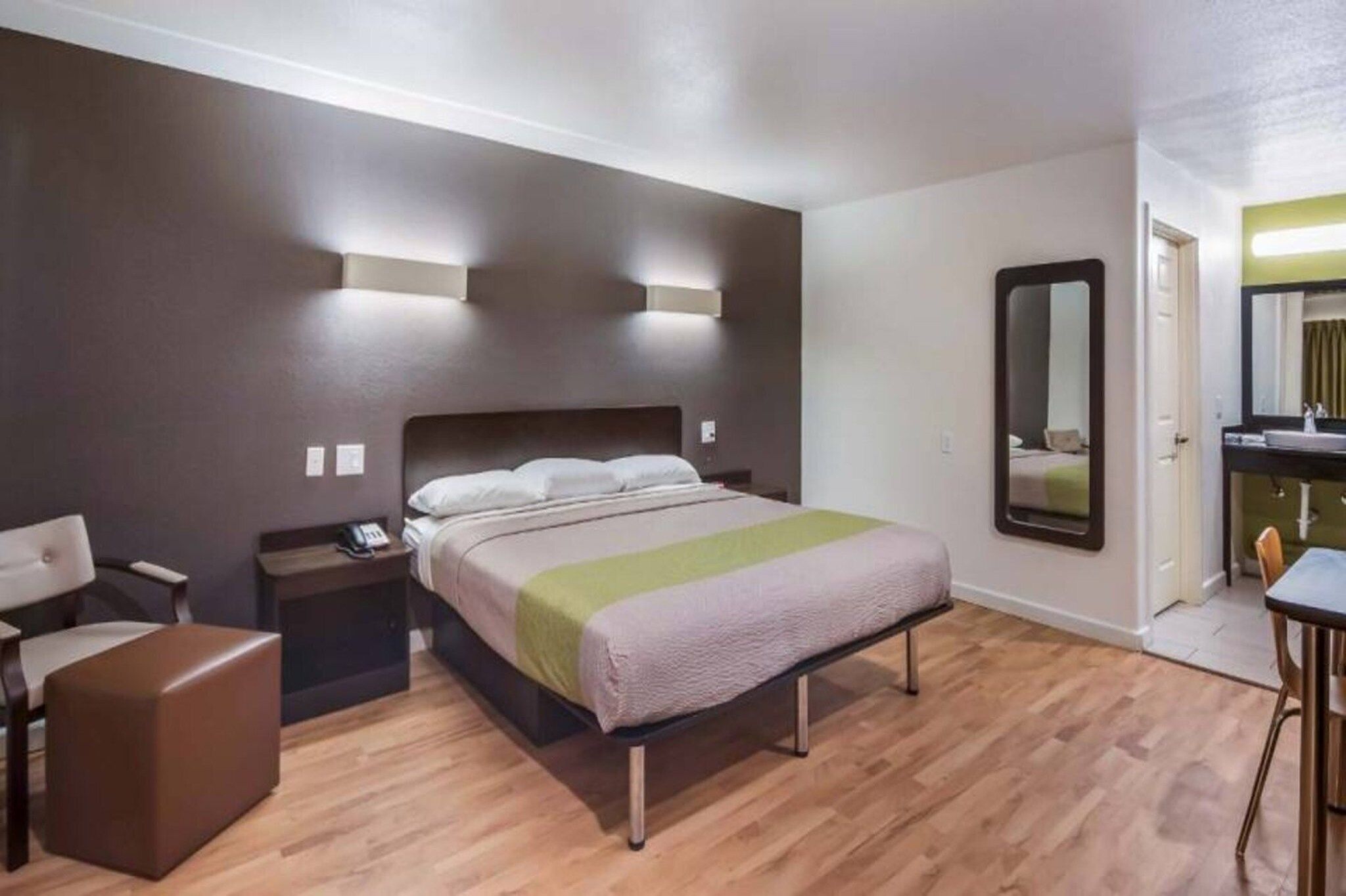 Een hotelkamer met een bed, nachtkastjes, een stoel, een bureau en een spiegel.