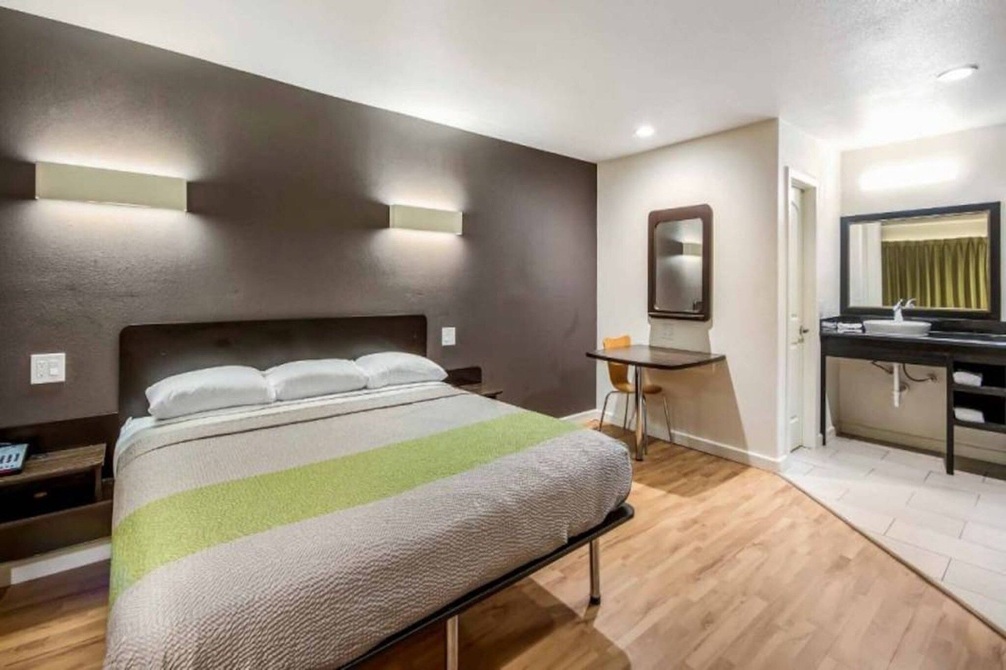 Une chambre d’hôtel comprenant un lit, un bureau, une chaise, un miroir et une salle de bain.