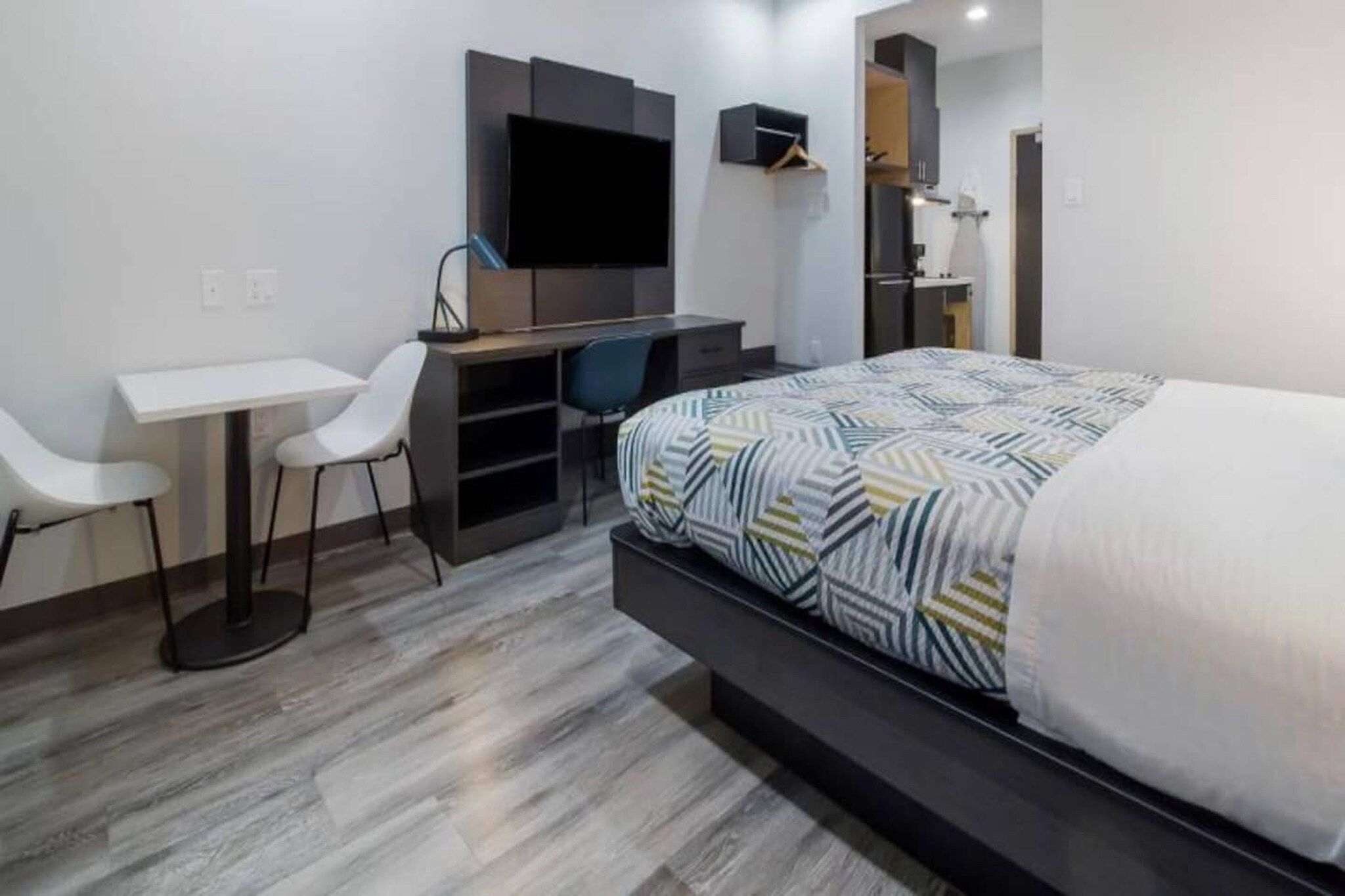 Una habitación de hotel moderna con cama, escritorio, silla y televisión.