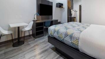 Una habitación de hotel moderna con cama, escritorio, silla y televisión.