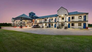 A motel with multiple rooms, a parking lot, and a grassy area in front.