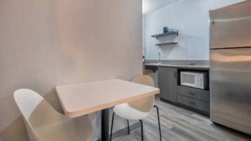 A modern kitchen with a stainless steel refrigerator, a microwave, and a small countertop.