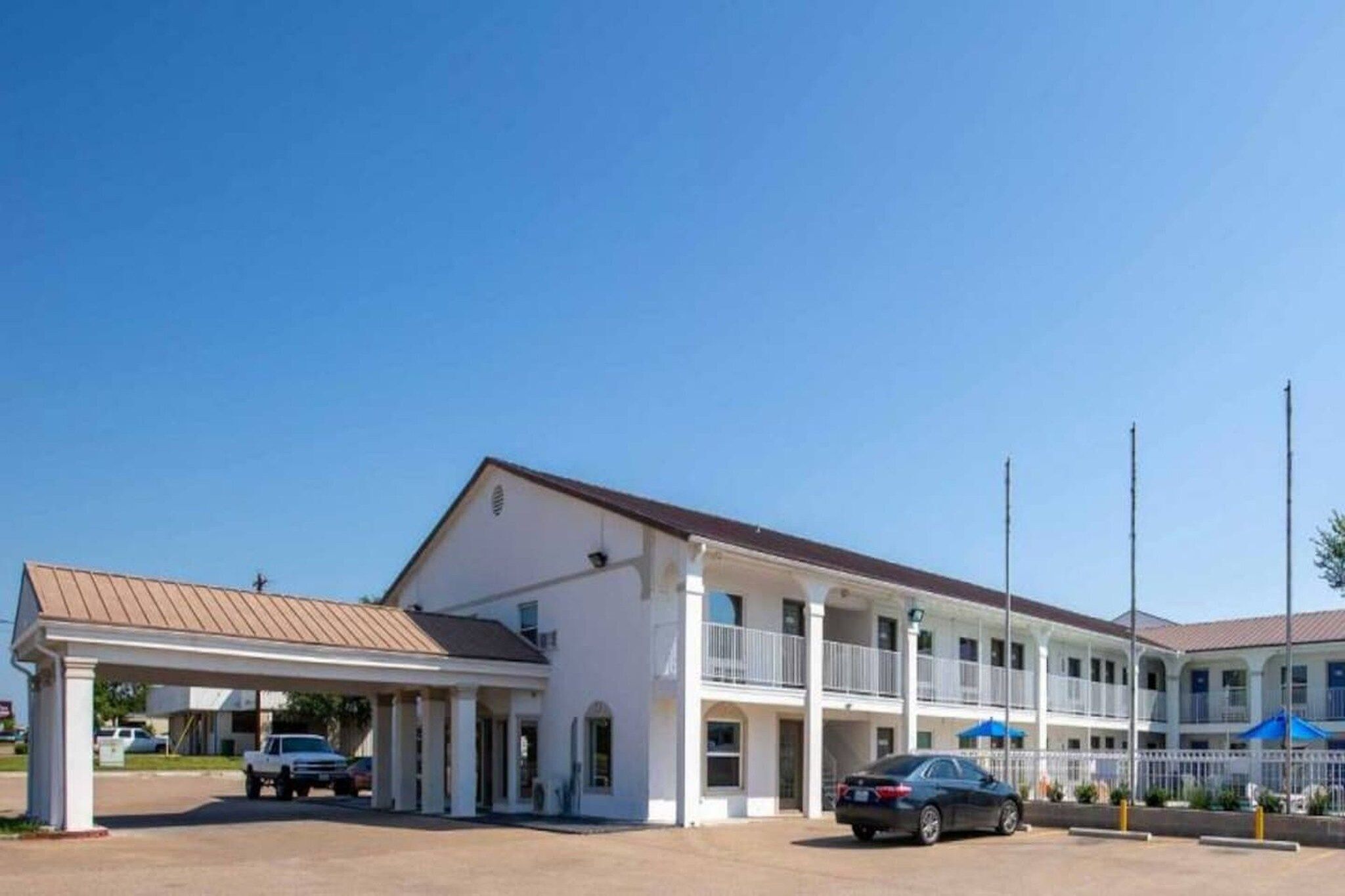 A two-story motel with a covered parking area and a car parked in front.
