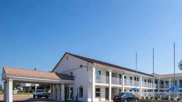 A two-story motel with a covered parking area and a car parked in front.