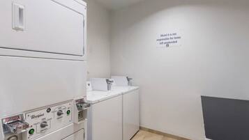 A laundry area with Whirlpool appliances, a sink, and a wall sign stating 'Motel is not responsible for items left unattended.'