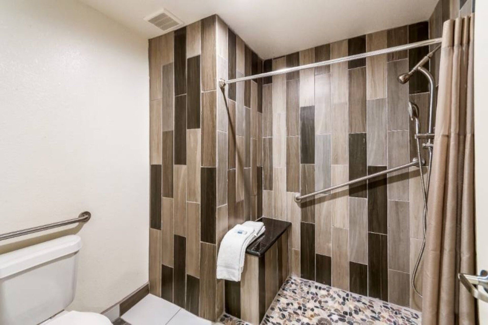 Un espace douche avec un mur recouvert de carreaux verticaux, un porte-serviettes et une pomme de douche.