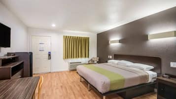 A hotel room with a bed, bedside table, and a desk with a chair.
