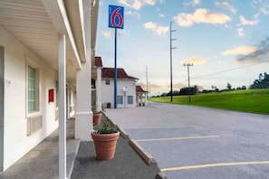 A motel with a parking lot, a building with a number '114' sign, and a '6' sign indicating the motel number. - 1 King Bed | Non-Smoking (Livingston)
