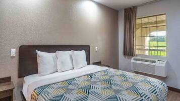 Een hotelkamer met een bed, een raam met gordijnen en een airconditioner.
