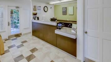 A reception area with a check-in counter, a clock, and a door.