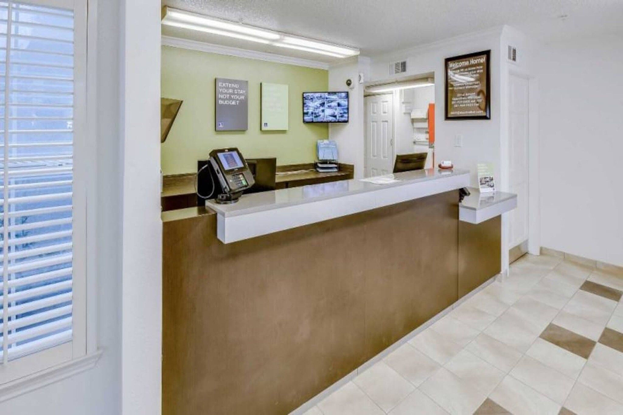 A reception desk with a telephone, a television mounted on the wall, and a framed sign.