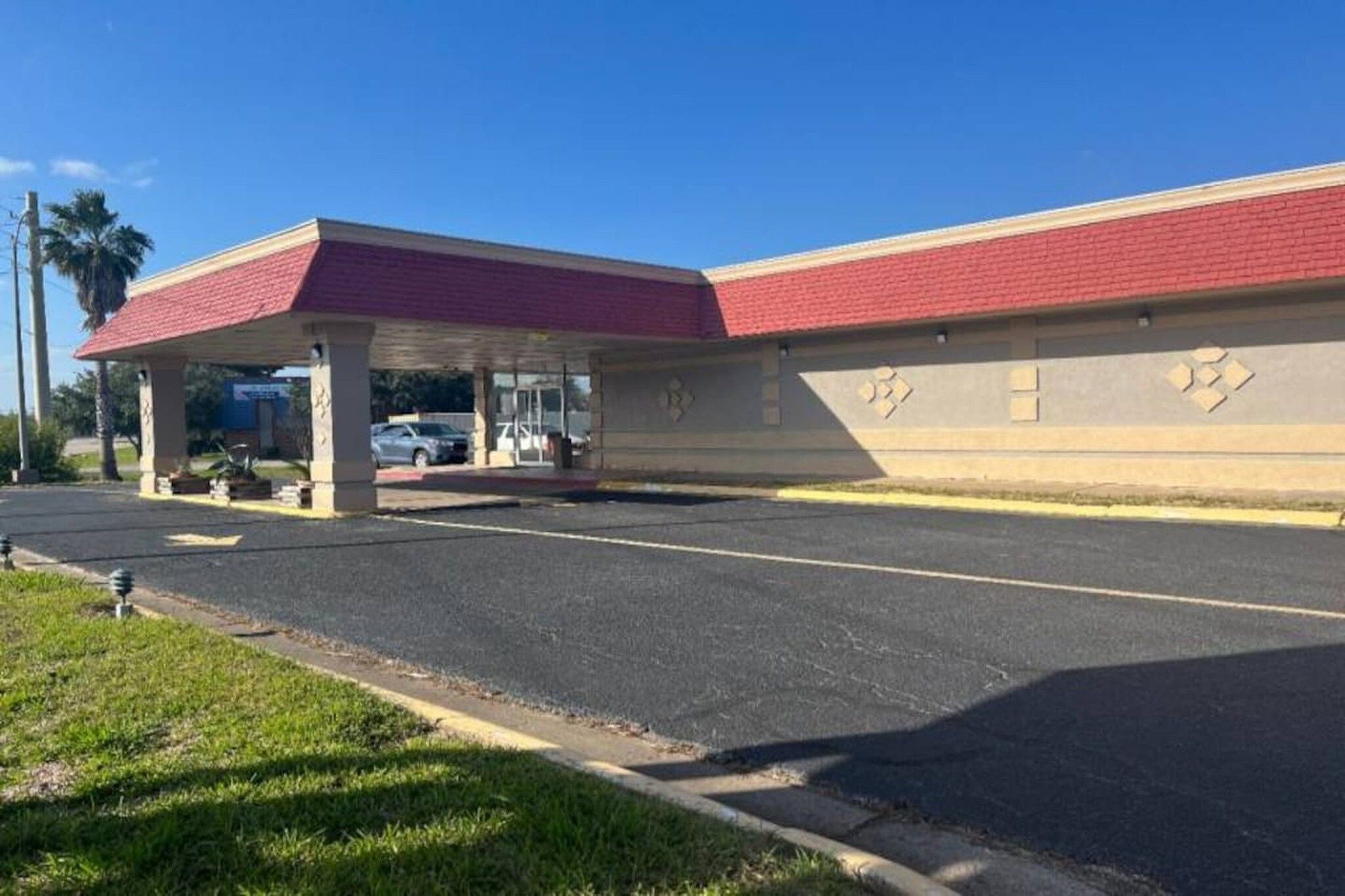 A building with a red roof and a covered parking area.
