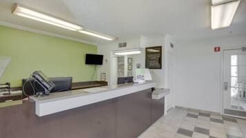 A reception desk with a flat-screen TV, a telephone, and a computer monitor. There is a framed certificate or award on the wall above the desk.