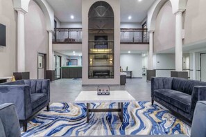 A spacious lobby with a marble-patterned floor, two sofas, a coffee table, and a fireplace. - Cozy King Bed|Pool|Free Parking (Brenham)