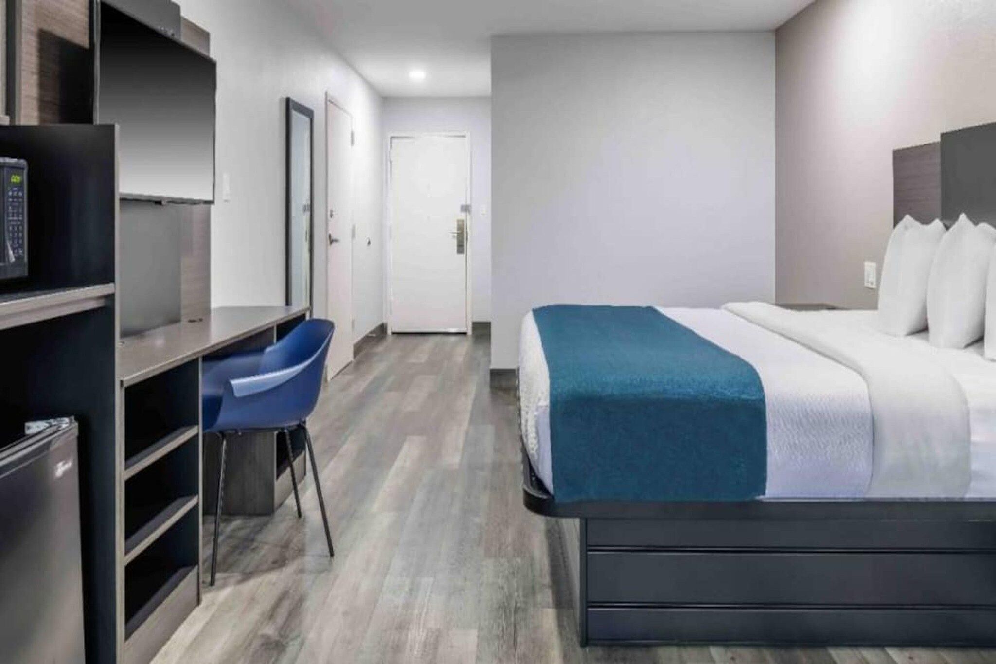 A hotel room with a bed, a desk, and a chair.