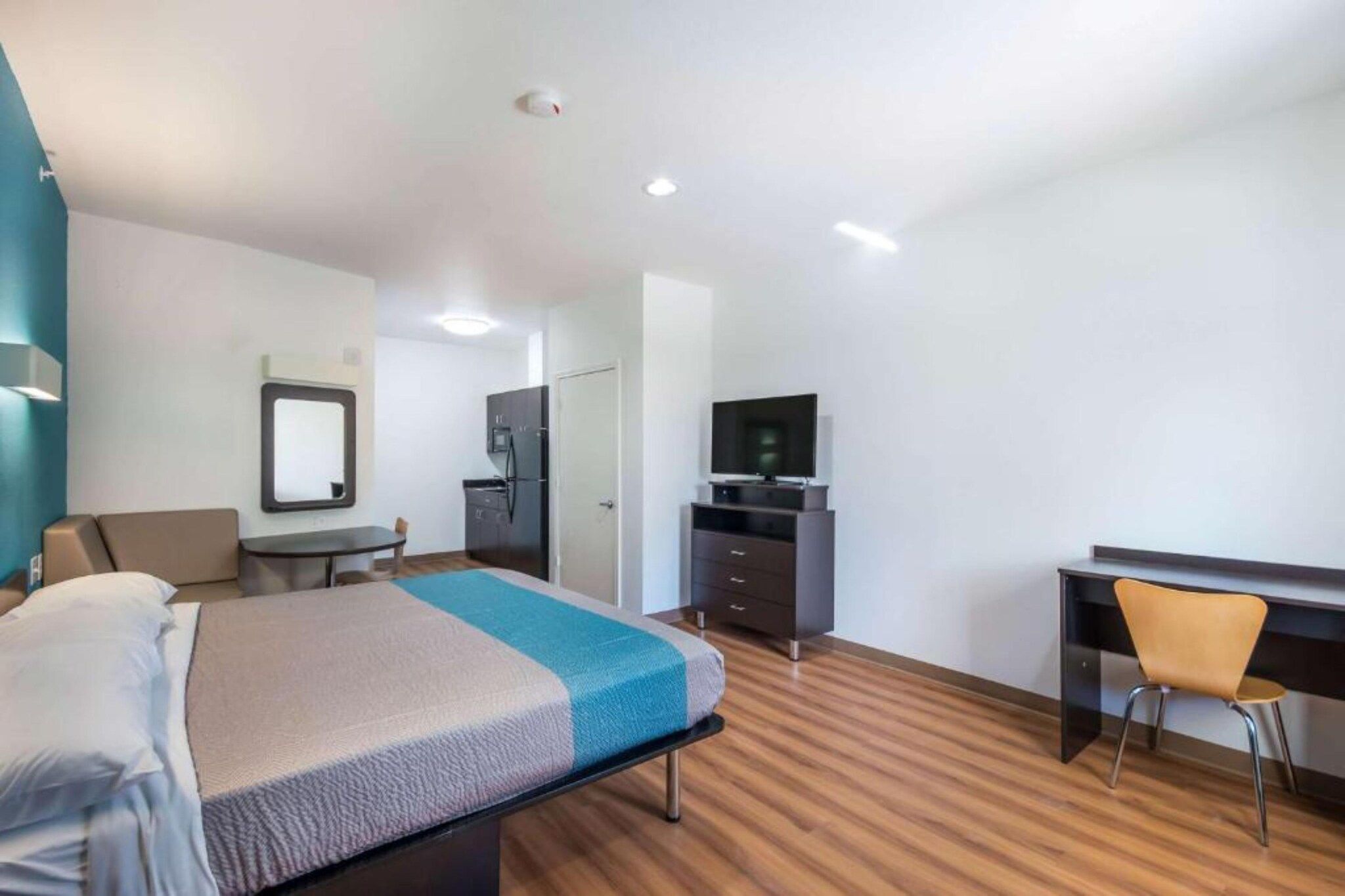 A hotel room with a bed, a desk, a chair, a television, and a wardrobe.