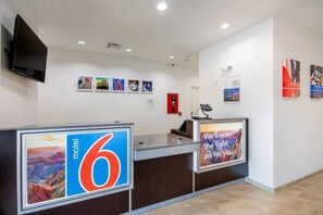 A motel reception desk with a large number '6' sign, a fire extinguisher, and a mounted television. - 1 king bed | suite, non-smoking, kitchen (Channelview)