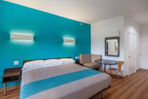 Ein Hotelzimmer mit einem großen Bett, einem Schreibtisch, einem Stuhl und einem Spiegel.