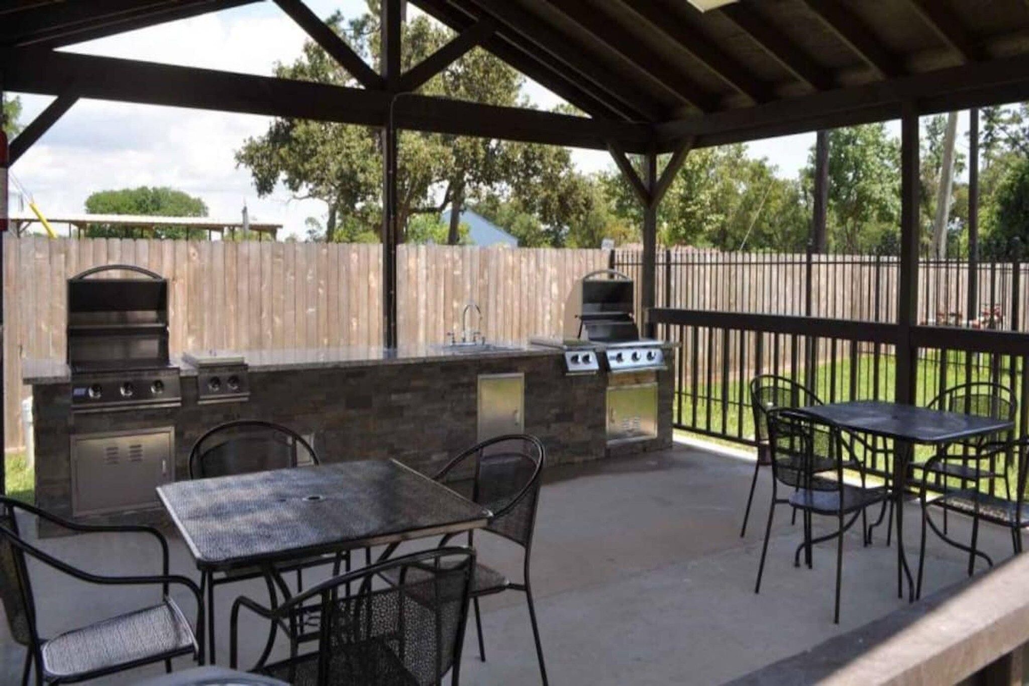 An outdoor patio with a grill, a table, and chairs.
