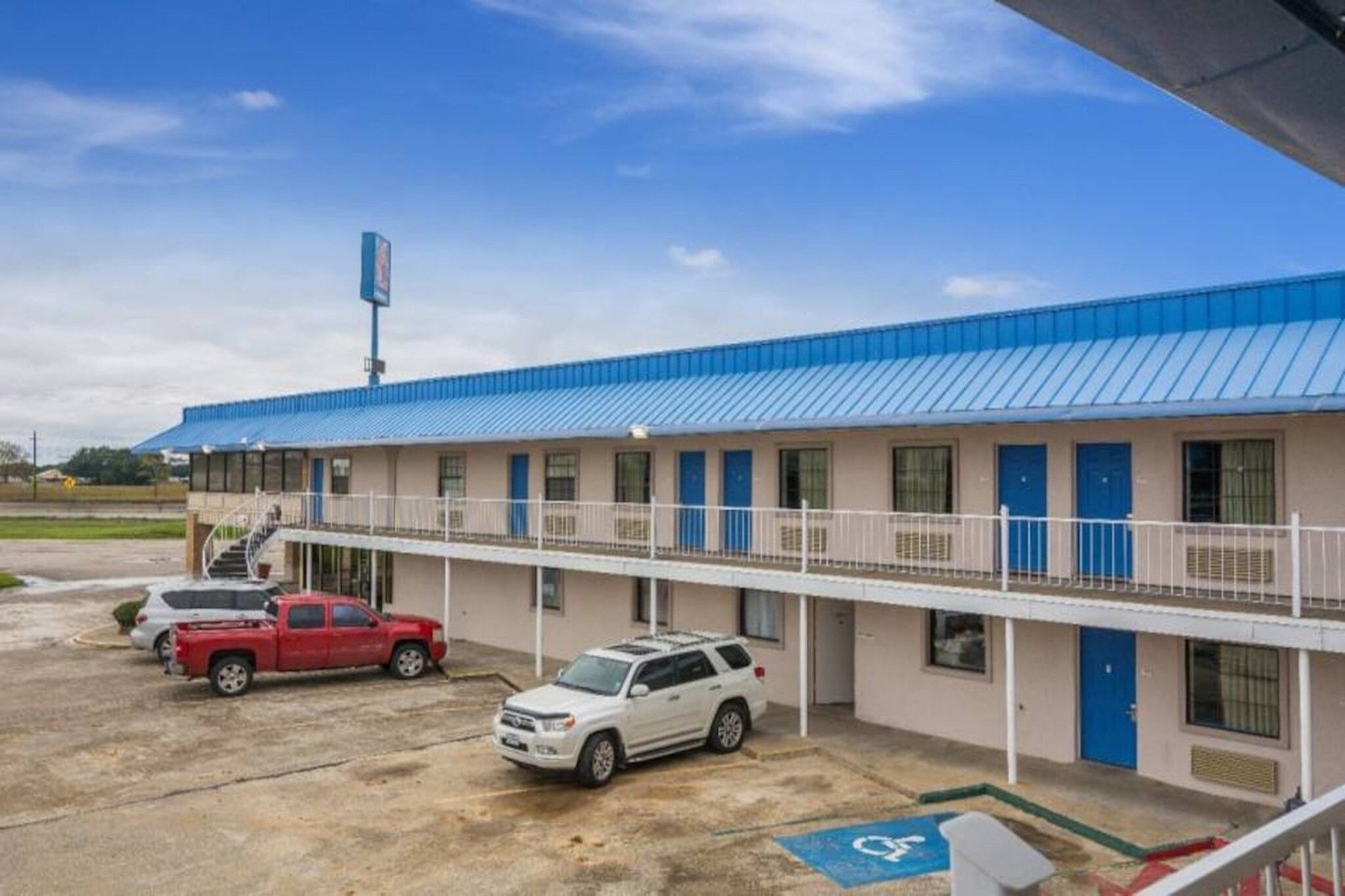 Ein Motel mit blauem Dach, einem Parkplatz und einem Stellplatz für Menschen mit Behinderung.