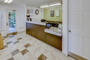 A reception area with a check-in counter, a clock, and a door. - 2 Full Beds | ADA/Tub, Nsmk (Houston)
