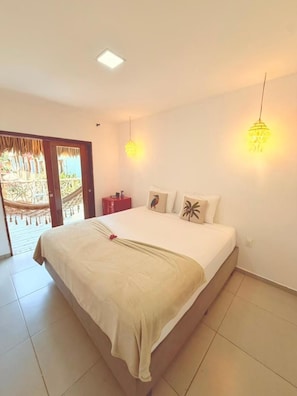 Een slaapkamer met een bed, een nachtkastje en een deur naar een balkon.