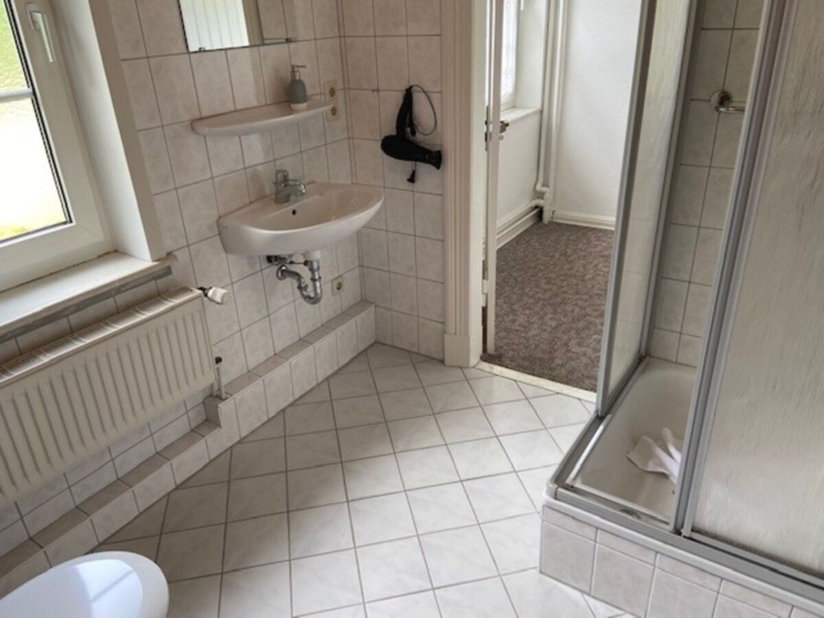Een badkamer met toilet, wastafel, douche en een radiator.