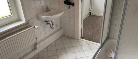Een badkamer met toilet, wastafel, douche en een radiator.