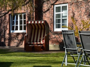 A brick building with a window, a striped outdoor chair, and a metal chair. - Holiday Apartment With 1 Bedroom (Wyk auf Foehr)
