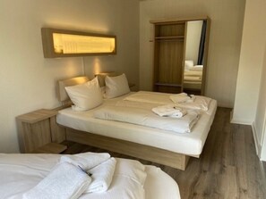 Ein Hotelzimmer mit einem Bett, Nachttischen, einem Kleiderschrank und einem Spiegel.
