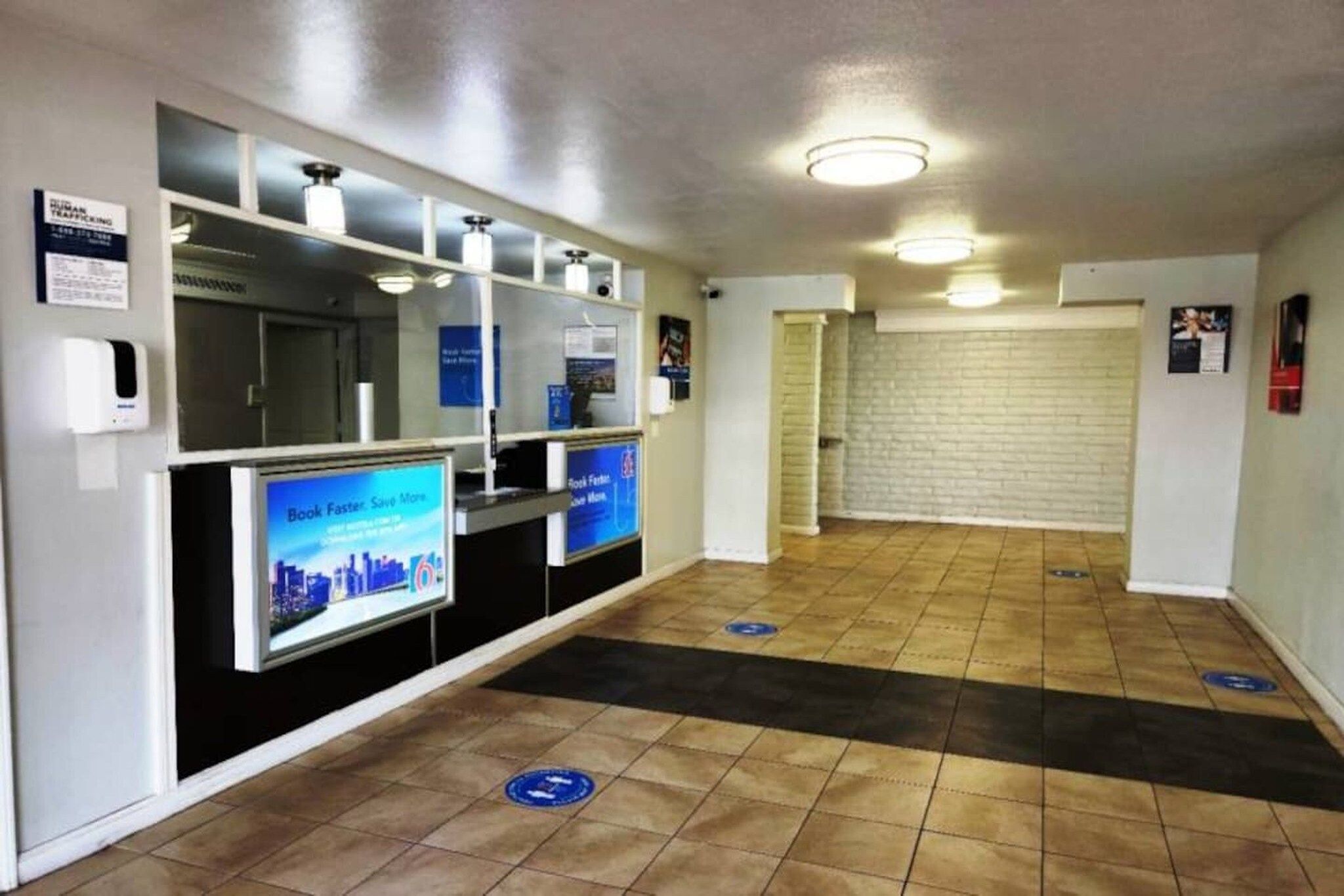 A reception area with a digital screen, a book return station, and a tiled floor with directional markers.