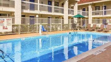 A swimming pool with a fenced area, a lifeguard stand, and a building with multiple balconies.