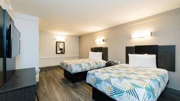 A hotel room with two beds, a TV, and a desk.