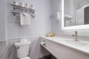 Ein Badezimmer mit Toilette, Waschbecken, Spiegel und Handtuchhalter mit Handtüchern.