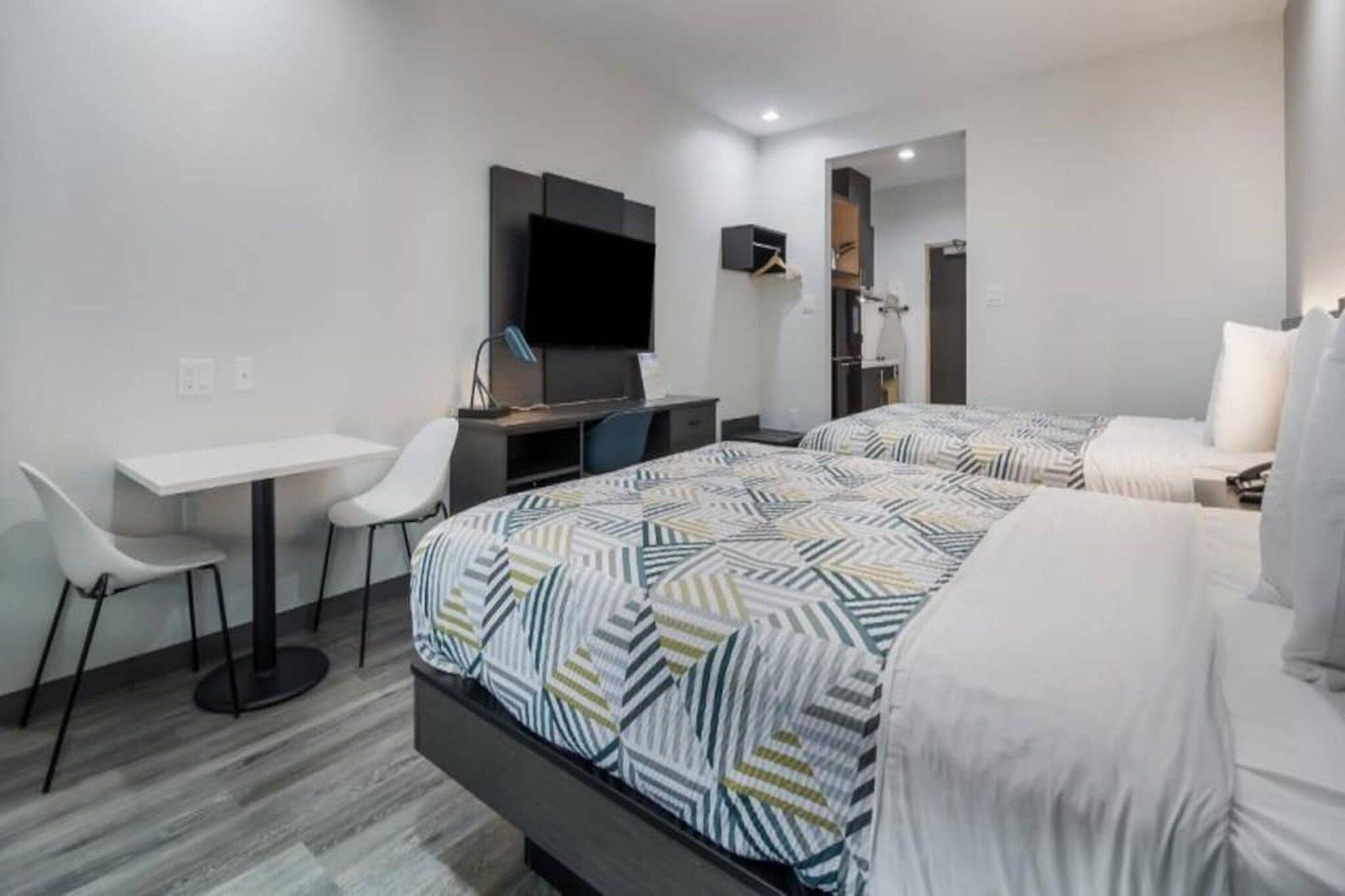 Una habitación de hotel moderna con una cama, escritorio, silla y televisor de pantalla plana.
