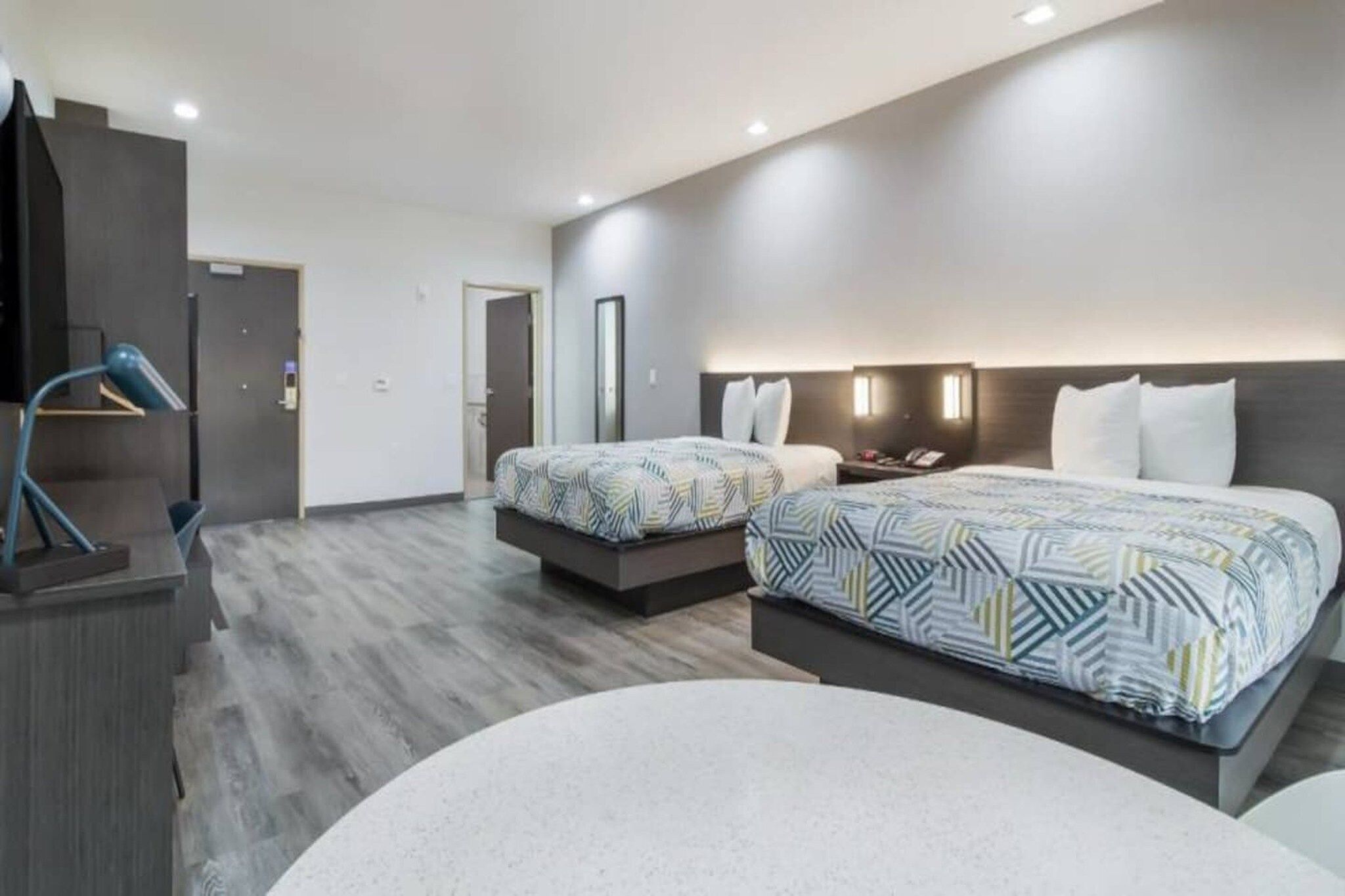 A hotel room with two beds, a desk, and a chair.