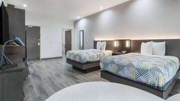 A hotel room with two beds, a desk, and a chair.