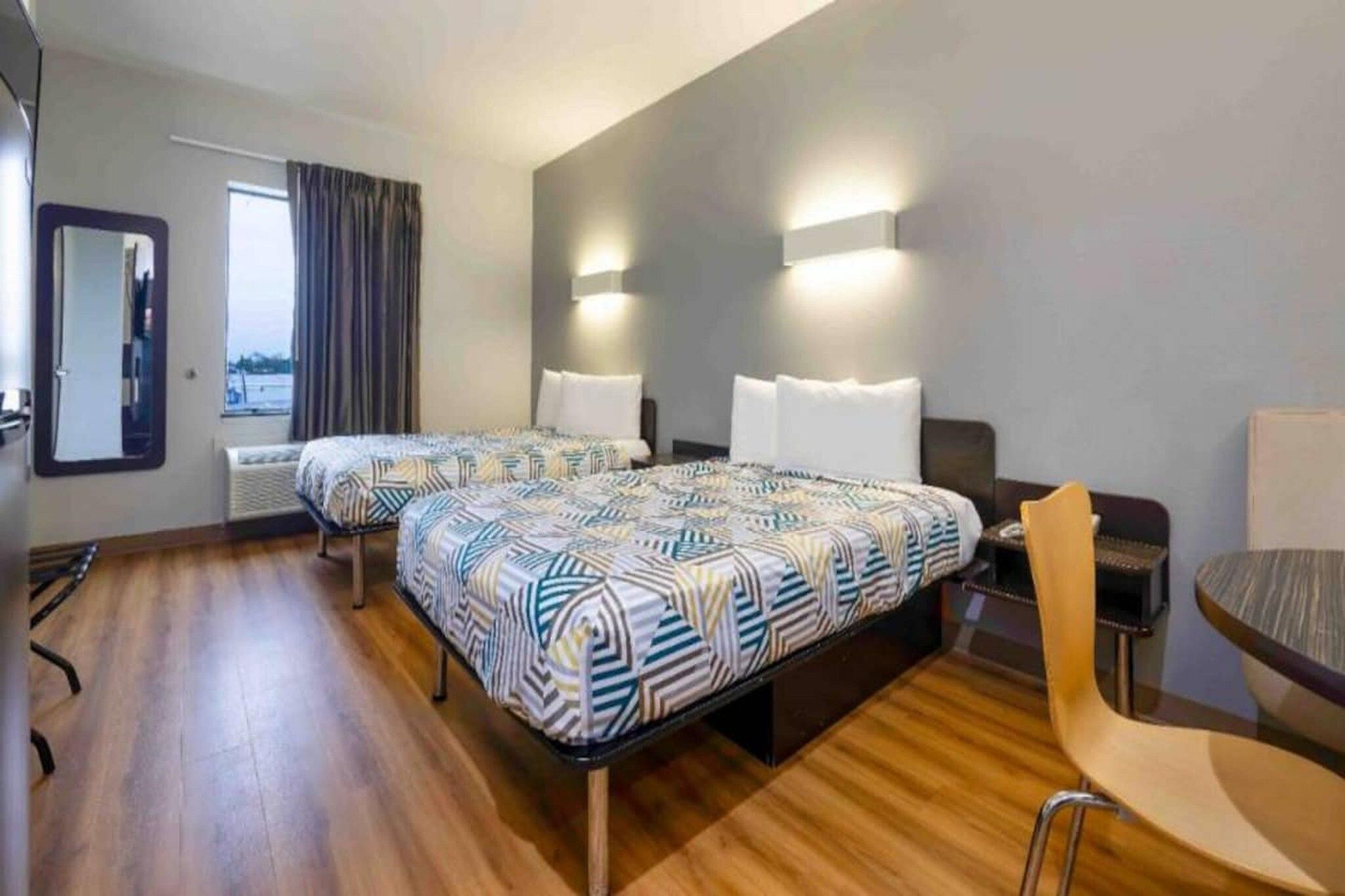 Hotellihuone, jossa on kaksi sänkyä, oleskelualue ja näkymä ulos.