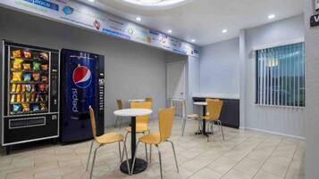 A cafeteria with vending machines, tables, and chairs.
