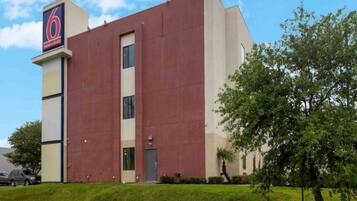 A modern building with a prominent '6' sign, a vertical entrance, and a well-maintained lawn.