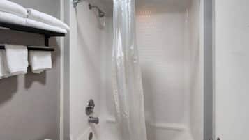 A bathroom with a shower, a toilet, and a shelf with towels.